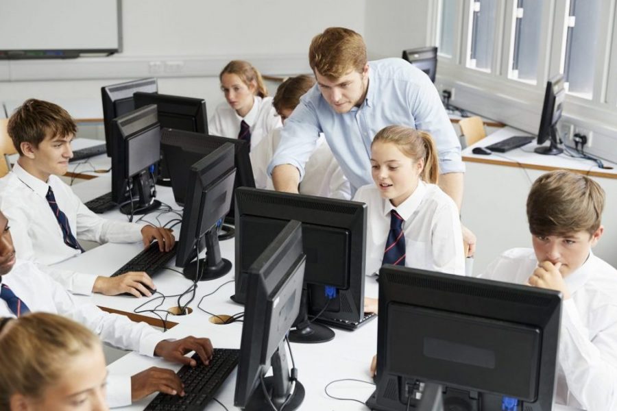 Teenage Students Wearing Uniform Studying In IT Class